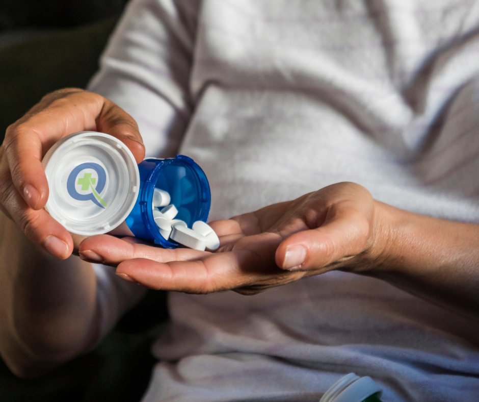 White medication pills scattered over hundred dollar bills with QuickRx logo representing c diff treatment costs and financial assistance